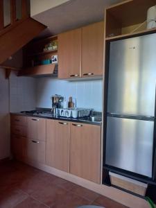 La cuisine est équipée d'armoires en bois et d'un réfrigérateur en acier inoxydable. dans l'établissement Appartement de vacances Marine de Bravone - Corse, à Linguizzetta