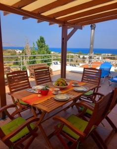 a wooden table and chairs on a patio with a view of the ocean at Katerinas Roof House in Gennadi