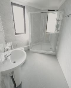 a white bathroom with a shower and a sink at Level Inn in Ebbw Vale