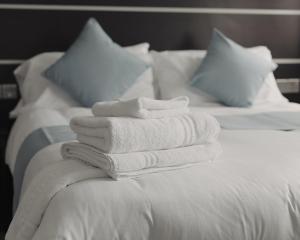 einen Stapel Handtücher auf dem Bett in der Unterkunft Level Inn in Ebbw Vale