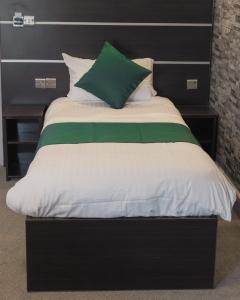 a bed with a black headboard and green and white pillows at Level Inn in Ebbw Vale