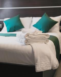 Bett mit weißer Bettwäsche und grünen Kissen in der Unterkunft Level Inn in Ebbw Vale