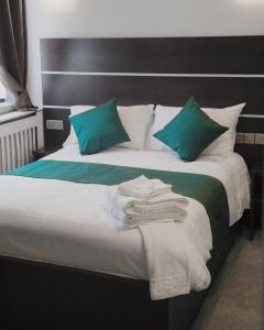 Una cama con almohadas verdes y toallas. en Level Inn, en Ebbw Vale