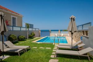 a villa with a swimming pool and chairs and an umbrella at Villa Anastasia Kalyves in Kalyves