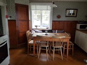 een keuken met een houten tafel met stoelen en een tafel en een tafel bij Charmig gård med bastu, strandtomt och utedusch i naturskönt område in Sveg