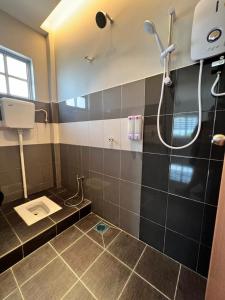 a bathroom with a shower and a tiled floor at Inn Homestay 2nd Floor Jasmine and Lavender unit in Teluk Intan