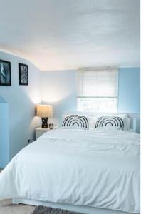 1 dormitorio con cama blanca y ventana en Destiny’s Place, en Franklin Square