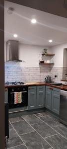 uma cozinha com armários cinzentos e um forno preto em The Stables em Skibbereen