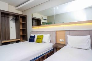 two beds in a room with a mirror at Urbanview Hotel Double Tree Purwokerto by RedDoorz in Purwokerto