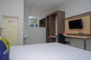 a room with a bed and a desk with a tv at Urbanview Hotel Double Tree Purwokerto by RedDoorz in Purwokerto
