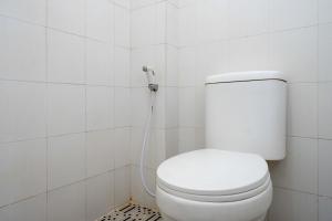 La salle de bains blanche est pourvue de toilettes et d'un tuyau. dans l'établissement Urbanview Hotel Double Tree Purwokerto by RedDoorz, à Purwokerto