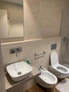 ein Badezimmer mit einem Waschbecken, einem WC und einem Spiegel in der Unterkunft [Riviera Apartments] Near the beach + Parking in Rosolina Mare