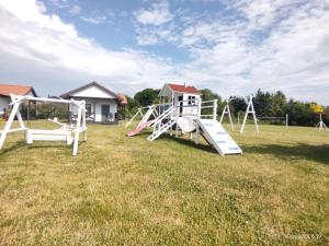 a playground with a slide in a grass field at Polne Domki in Darłowo