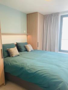 een slaapkamer met een groot blauw bed met 2 kussens bij C-dream in Blankenberge