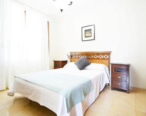 1 dormitorio con cama blanca y tocador de madera en Casa con precioso jardín en Vilanova de Arousa, en Villanueva de Arosa