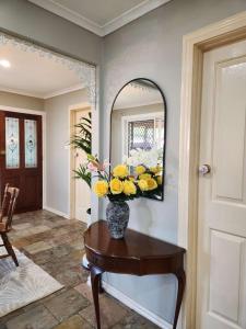 a vase of yellow and white flowers on a table in a hallway at Home in Frankston in Frankston