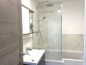 een witte badkamer met een douche en een wastafel bij Beachside Apartment 1 Porthcawl in Porthcawl