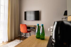 dwie zielone butelki na stole z biurkiem i telewizorem w obiekcie Apartamenty Na Skarpie w mieście Płock