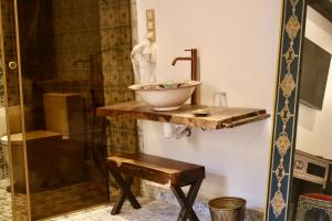 a bathroom with a sink on a wooden counter with a shower at Riad Mellah in Essaouira
