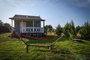 a hammock in front of a small house at Pogodny domek in Kołczewo +13 photos