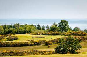 a view of a golf course with the ocean in the background at Österlens Golfklubb - Lilla Vik in Simrishamn