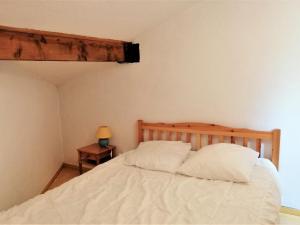- une chambre avec un lit doté de draps blancs et d'une tête de lit en bois dans l'établissement Appartement Morillon 1100, 3 pièces, 5 personnes - FR-1-412-19, à Morillon