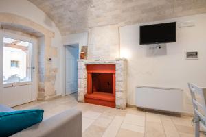 a living room with a fireplace and a tv on a wall at Trullo il Focolare in Masseria in Cisternino