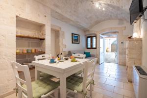 a kitchen and dining room with a white table and chairs at Trullo il Focolare in Masseria in Cisternino