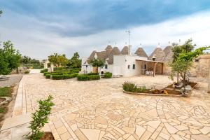 a stone courtyard with a house with thatched roofs at Trullo il Focolare in Masseria in Cisternino