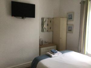 a bedroom with a bed and a flat screen tv on the wall at Seacrest Guest House Room Only in Whitby