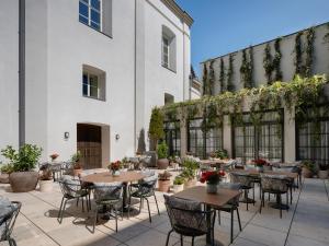 an outdoor patio with tables and chairs and a building at Stradom House, Autograph Collection in Krakow