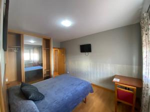 a bedroom with a blue bed and a television on the wall at dpCristal Castelao in Sarria