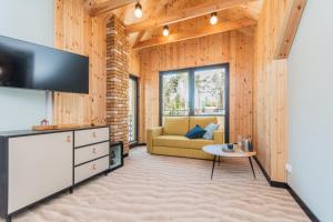 a living room with a television and a couch at Wiatr od morza Jantar - BursztynoveLove in Jantar