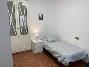 sypialnia z łóżkiem i nocną szafką z lampką w obiekcie Piso grande de 120 m2, a 15' de la playa en coche w mieście Huelva