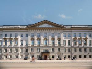 een groot wit gebouw met mensen op een fiets voor bij Stradom House, Autograph Collection in Krakau