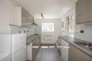 een witte keuken met witte apparatuur en een houten vloer bij Spacious Serenity in the Heart of Central London in Londen