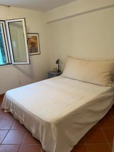 a white bed in a room with a window at Villa House 200 with sea view in Spetses