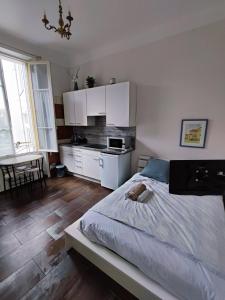 1 dormitorio con 1 cama y cocina con armarios blancos en Appartement idéalement situé pour curiste, en Châtel-Guyon