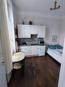 a kitchen with white cabinets and a table and a bed at Appartement idéalement situé pour curiste in Châtel-Guyon