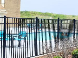 a fence with a table and chairs in front of a pool at Home2 Suites by Hilton Outer Banks Kill Devil Hills in Kill Devil Hills