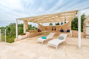 a pavilion with two chairs and a table on a patio at Trullo Suite in Masseria in Cisternino