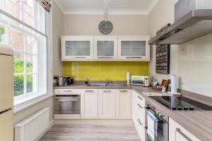 a kitchen with white cabinets and a yellow wall at Spacious Apt in the Heart of York I Pass The Keys in York
