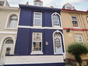 a blue house with white trim in front of buildings at 27 Exeter Street in Teignmouth