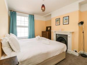 27 Exeter Street في تيغنماوث: غرفة نوم مع سرير أبيض كبير مع موقد