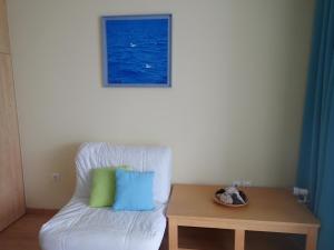 uma cadeira branca com duas almofadas e uma mesa em Beachfront Studio with Private Path to the Sea em Poros