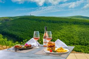 a table with two glasses of wine and a hamburger at Hotel Ózon & Luxury Villas in Mátraháza