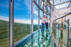 een man en vrouw die op de glazen vloer van een gebouw staan bij Hotel Ózon & Luxury Villas in Mátraháza