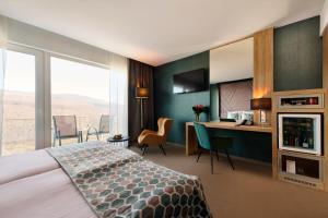 Cette chambre comprend un lit et un bureau. dans l'établissement Hotel Ózon & Luxury Villas, à Mátraháza
