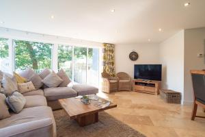 a living room with a couch and a tv at Trewhiddle Retreat V25 by Together Travel - Luxury 4-Bedroom Villa in St Austell