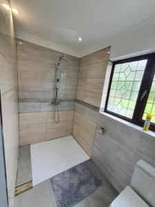 baño con ducha, aseo y ventana en Bungalow in leafy area, en Upminster